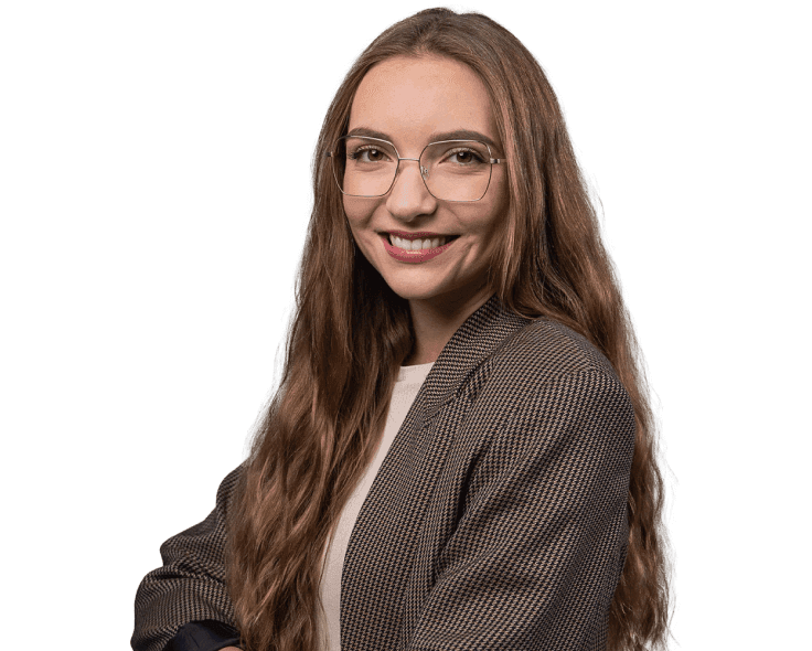 A smiling woman with glasses in a brown checkered blazer.