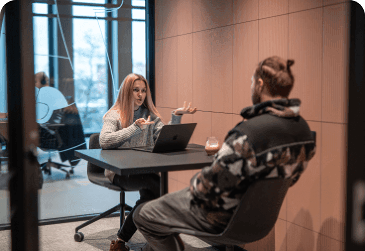 A man and a woman sitting at a square table and talking.