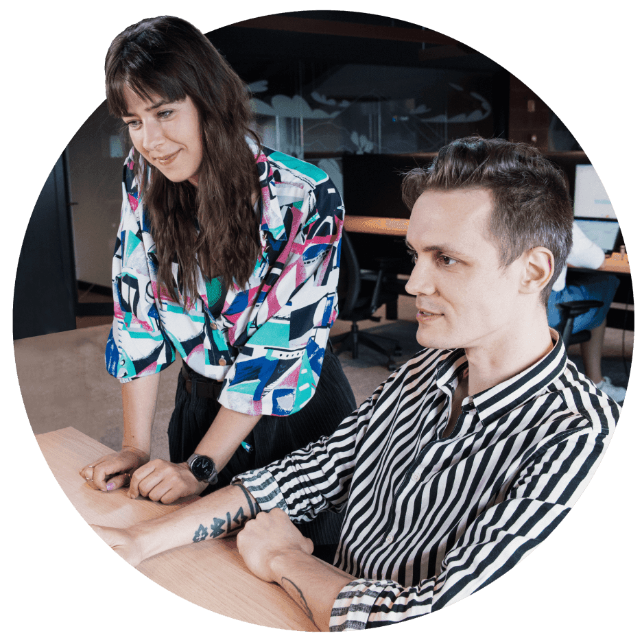 A smiling man and a woman looking at computer monitors.